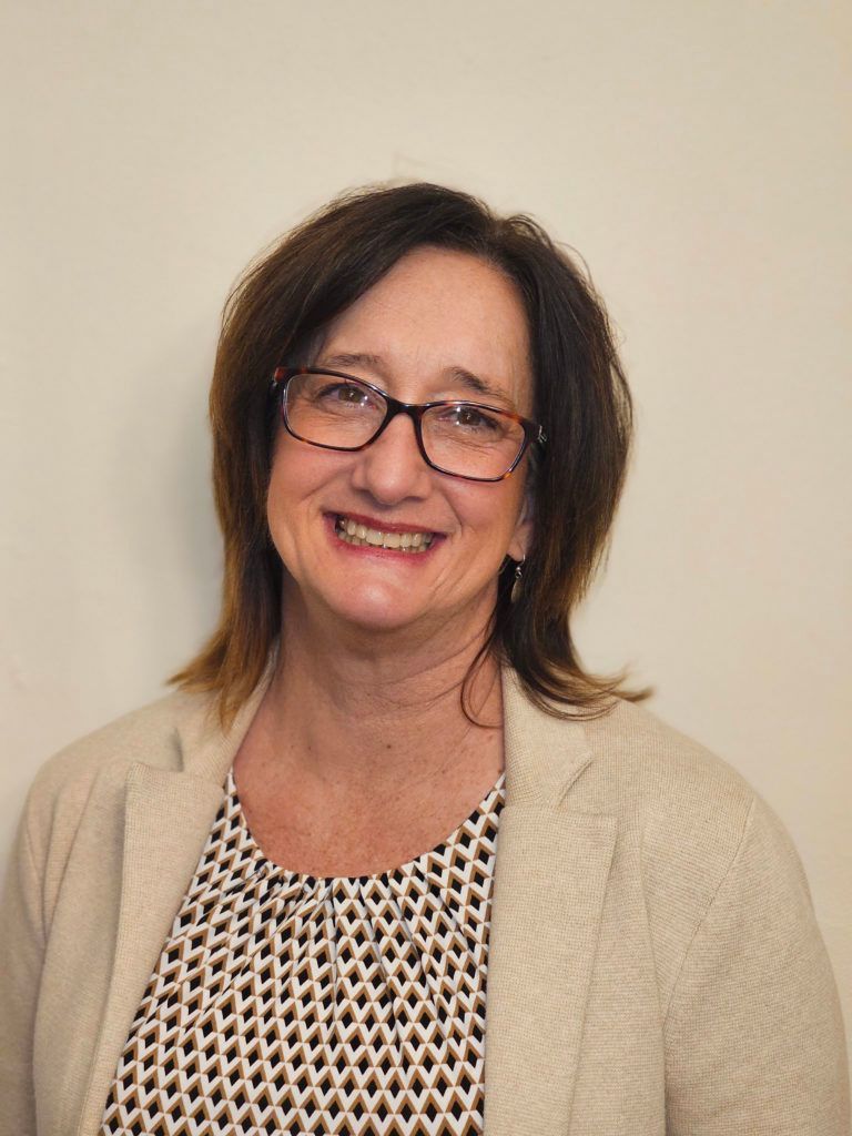A woman with glasses is smiling.