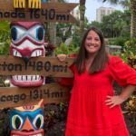 Woman standing next to tiki while smiling at the camera.