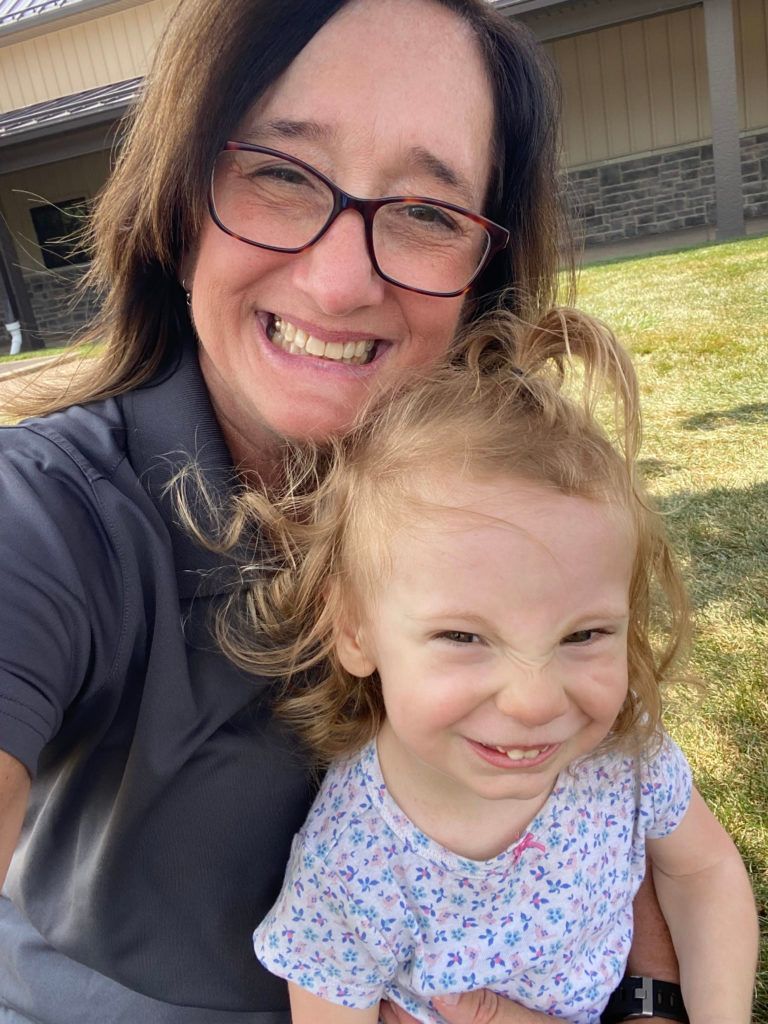 A woman with glasses holds a smiling child.