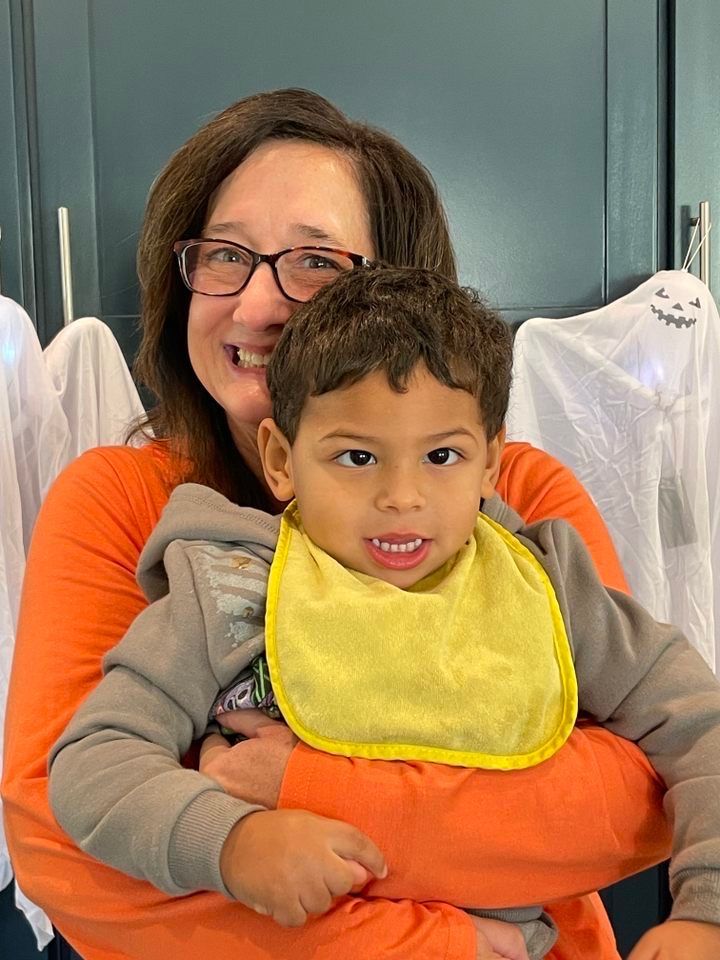 A woman holds a boy while both smile.