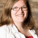 Woman with glasses smiling at the camera.