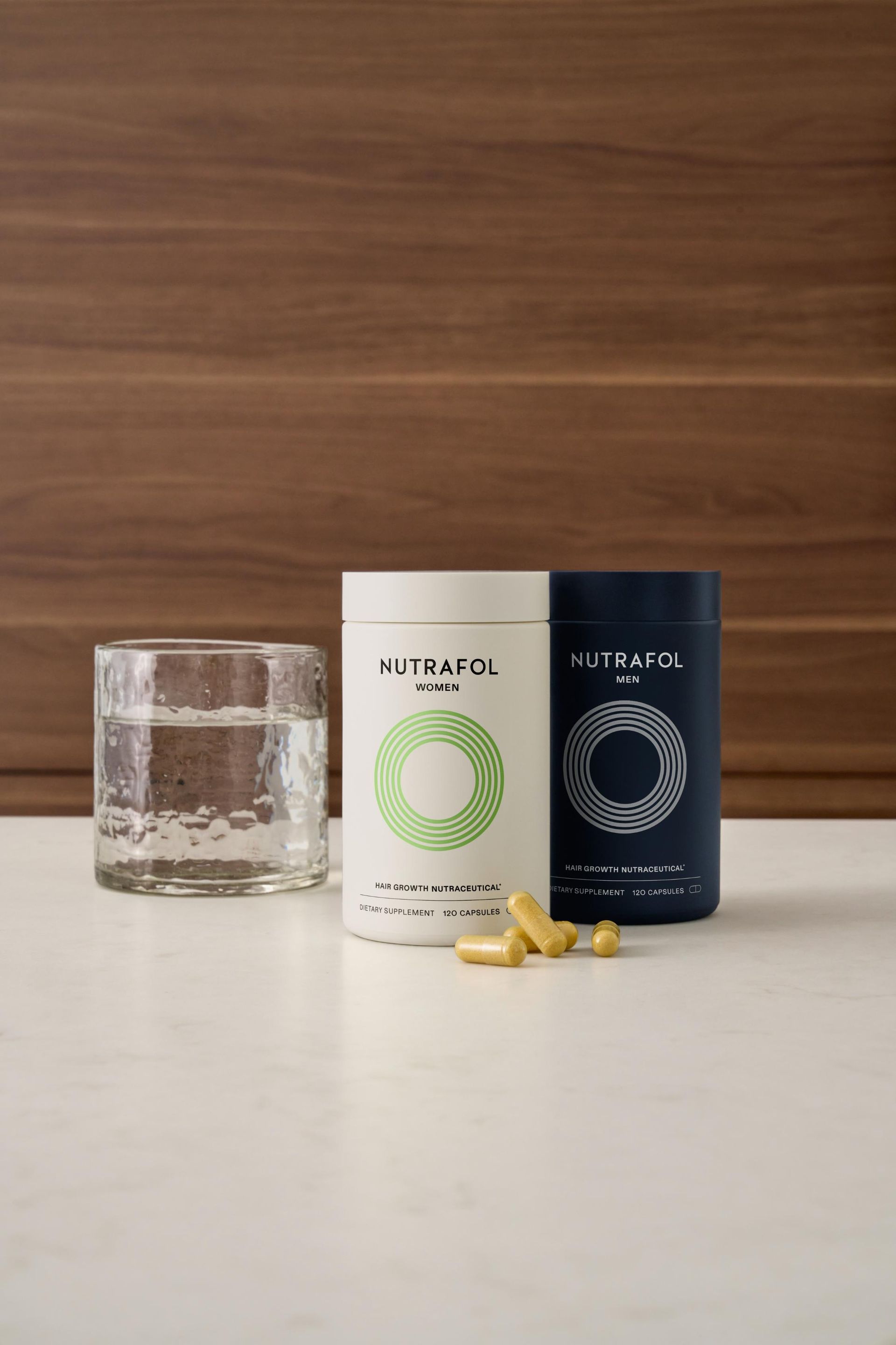 Two containers of pills and a glass of water on a table.