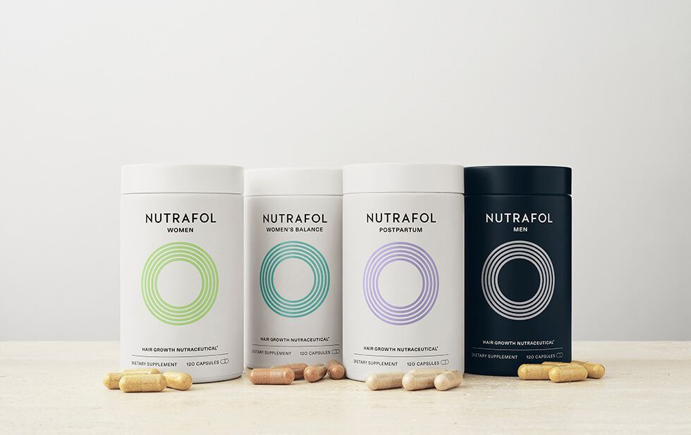 Four bottles of pills are sitting on a wooden table.