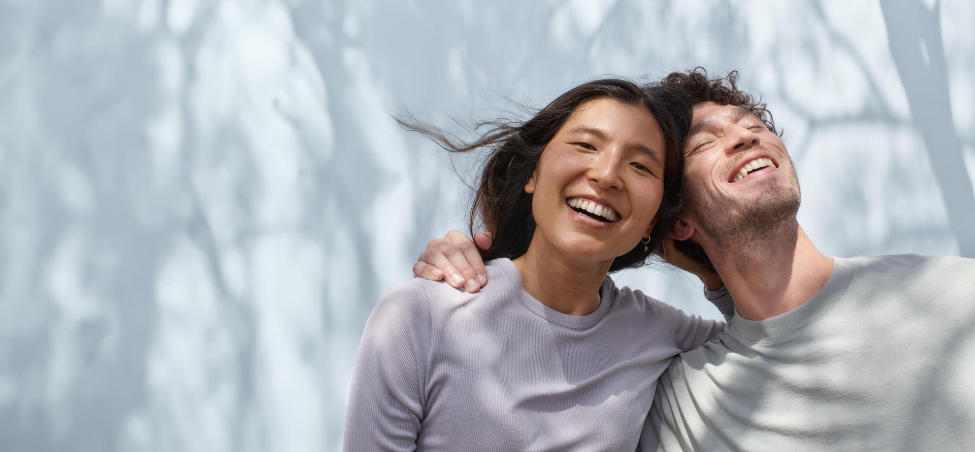 A man and a woman are hugging each other and smiling.