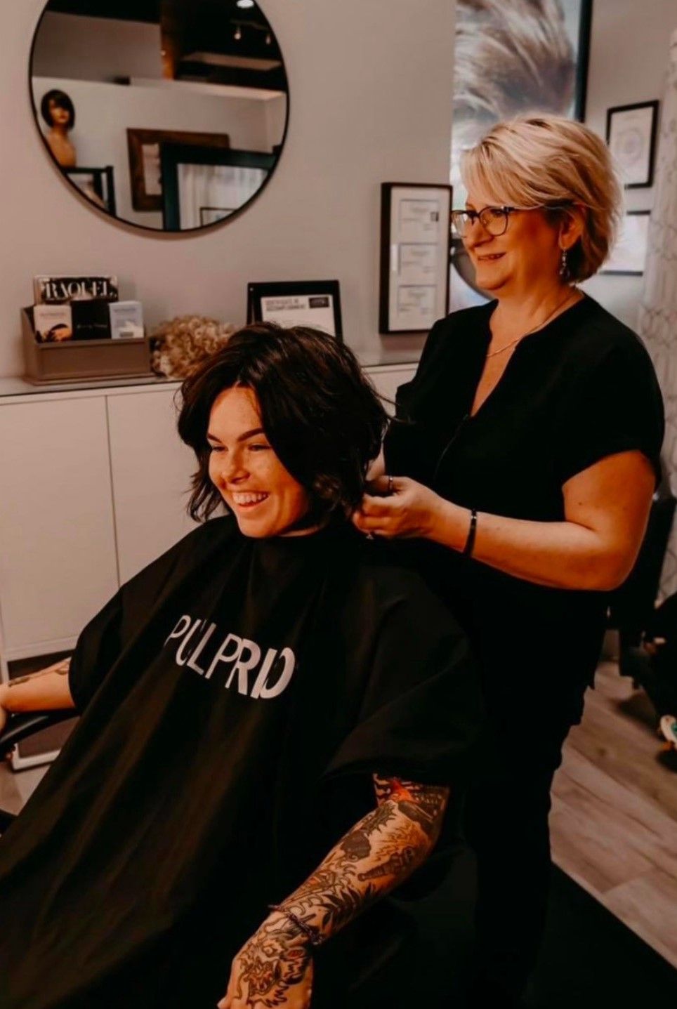 A woman is cutting a man 's hair in a salon.