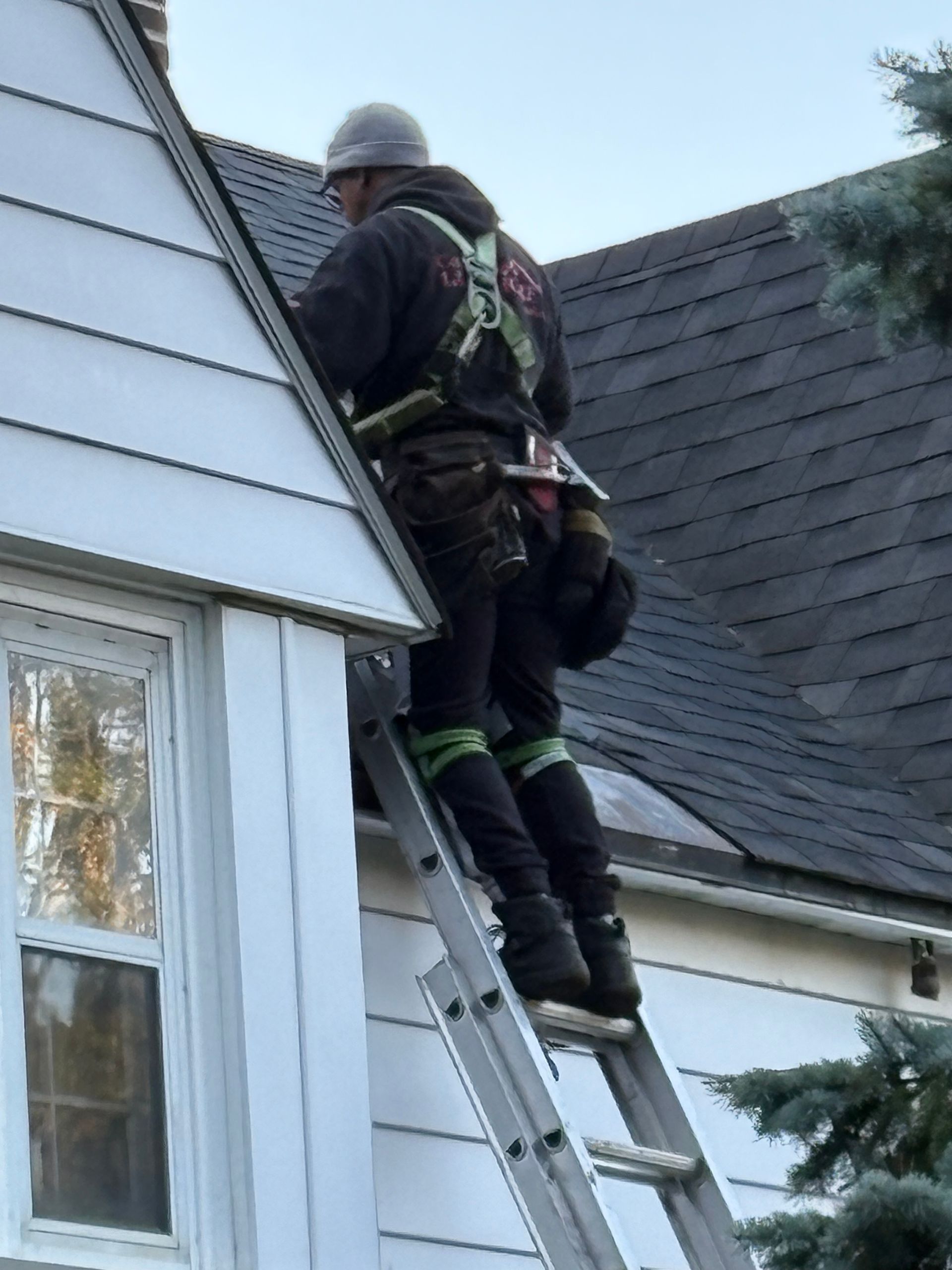Un pompier monte à l'échelle pour atteindre le toit d'une maison lors d'une intervention d'urgence.