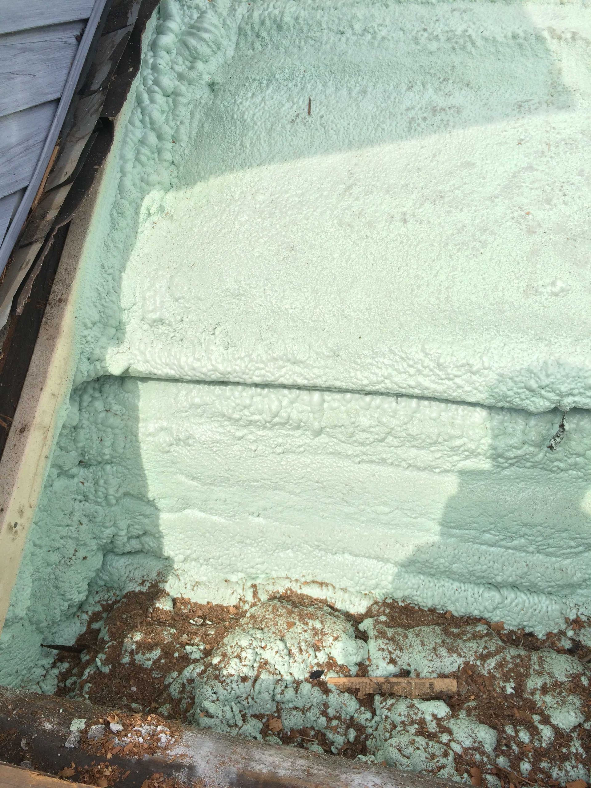 Mur extérieur vert menthe avec peinture écaillée et base rouillée près d'un angle