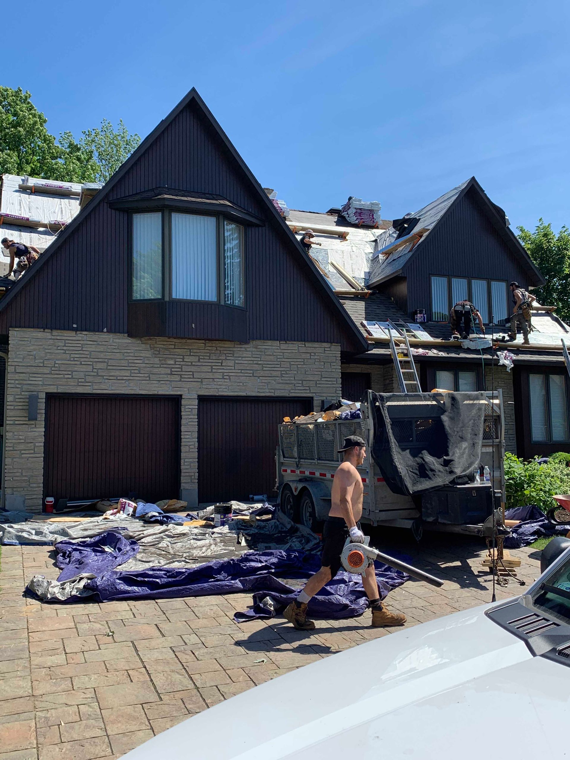Maison endommagée, toit brûlé et débris devant, une personne se tenant sur l'allée.