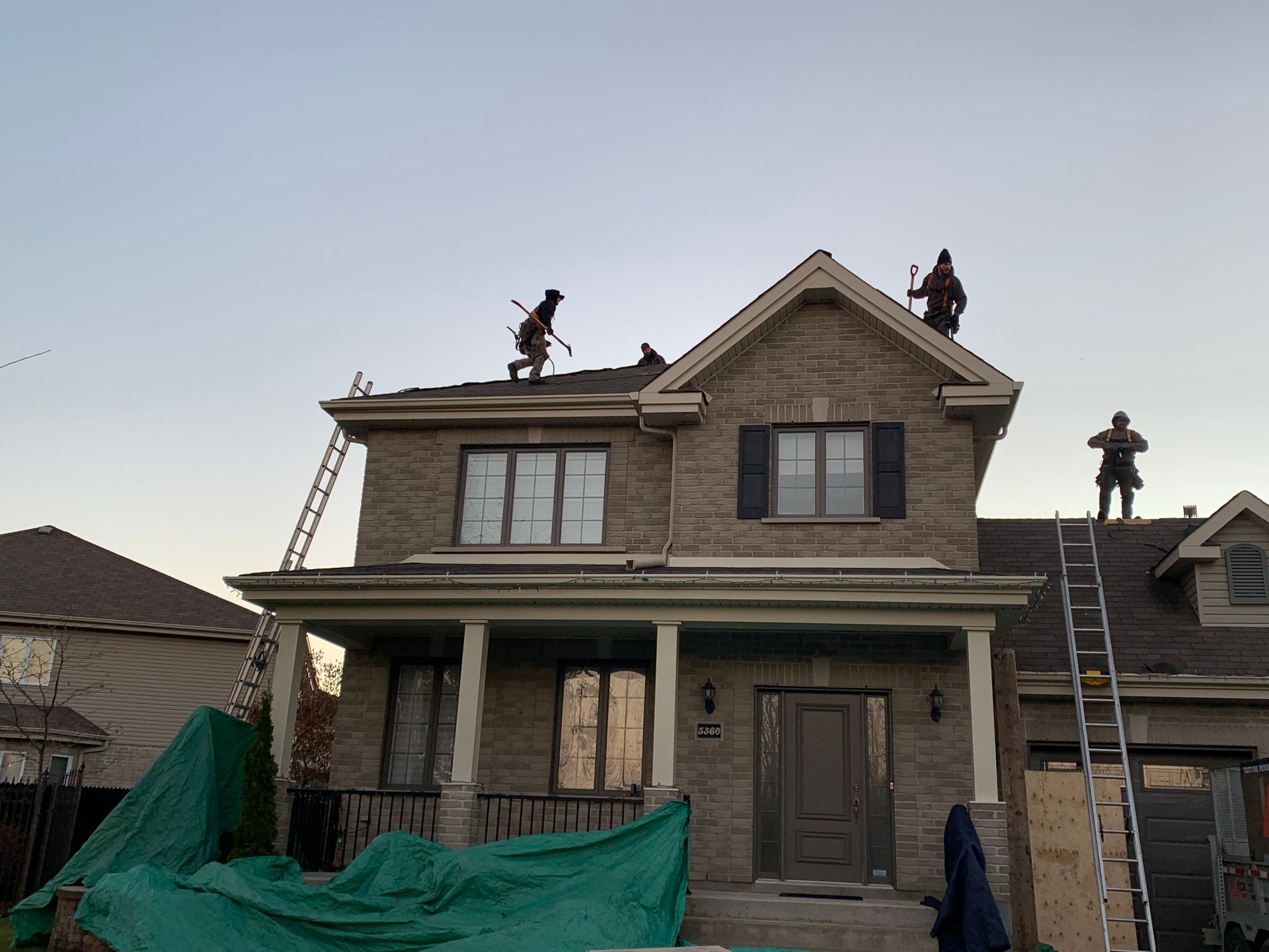 Maison en construction avec deux ouvriers sur le toit et une échelle à l'entrée principale