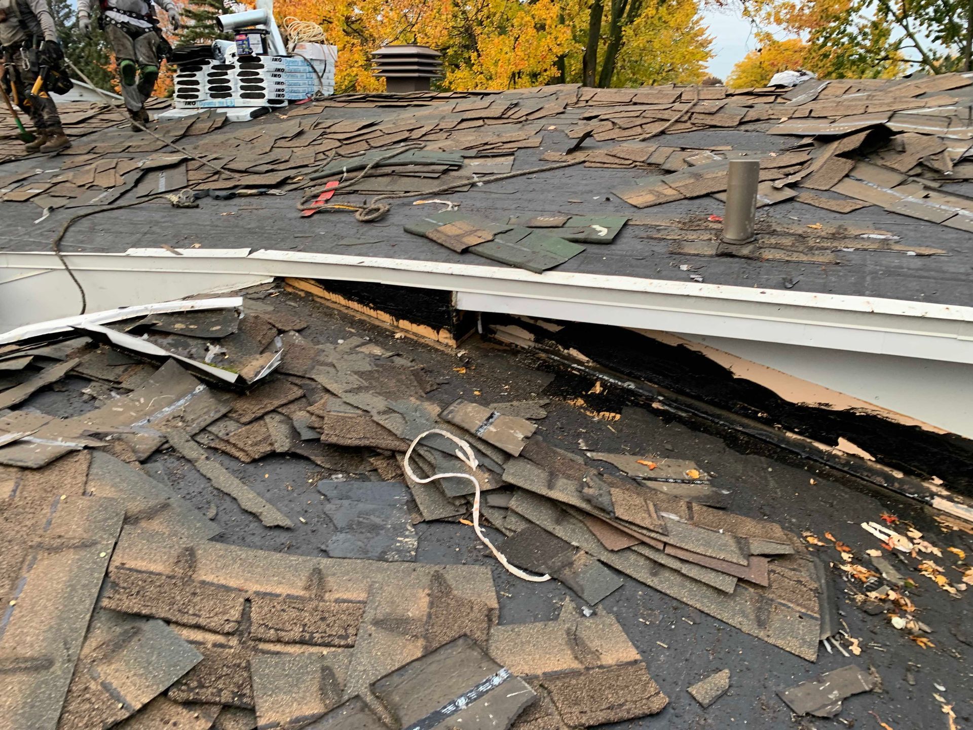 Toiture en bardeaux effondrée, présentant un large trou laissant apparaître une sous-couche endommagée et des débris.