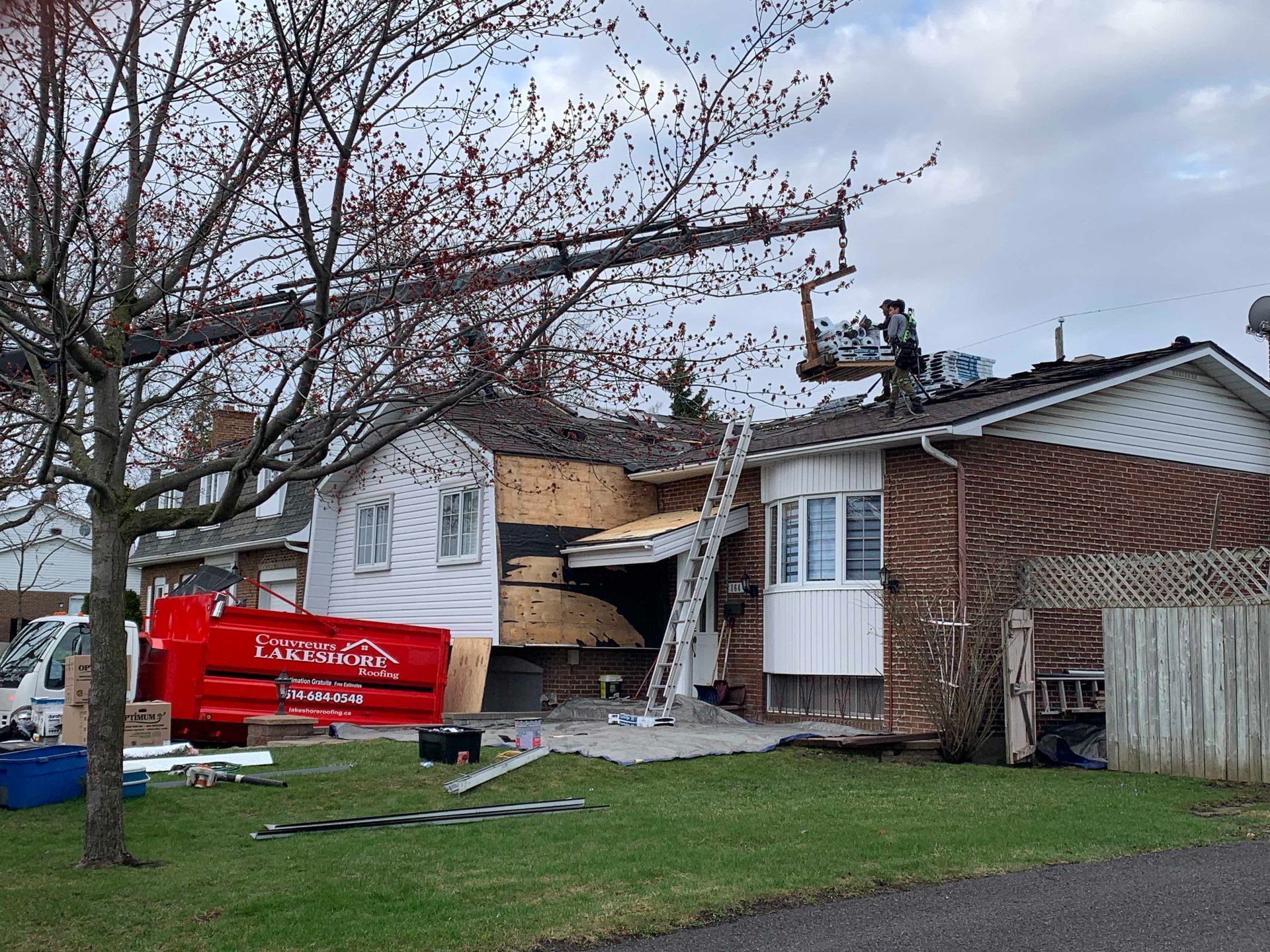 Maison gravement endommagée par une tempête, toit exposé et débris, à côté d'un camion utilitaire rouge dans la cour avant