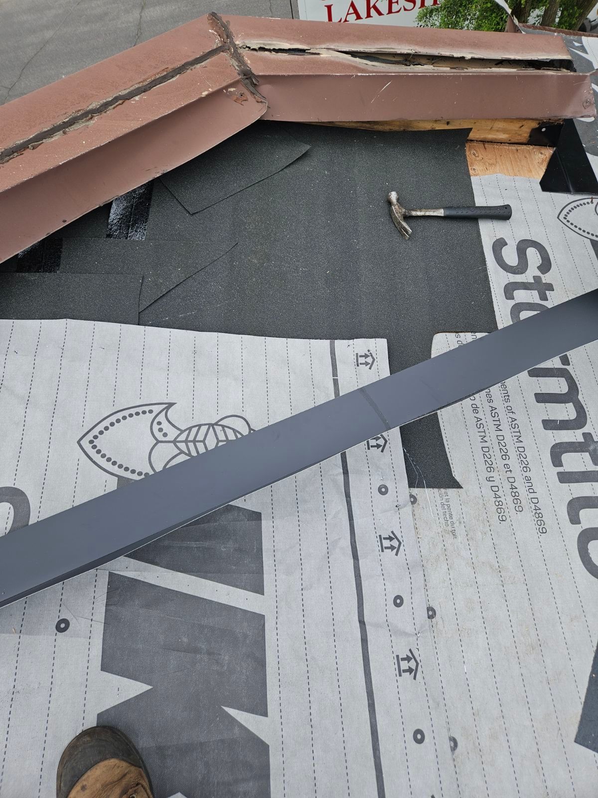 Bardeaux et sous-couche de toiture posés au marteau sur une charpente de toiture partiellement installée