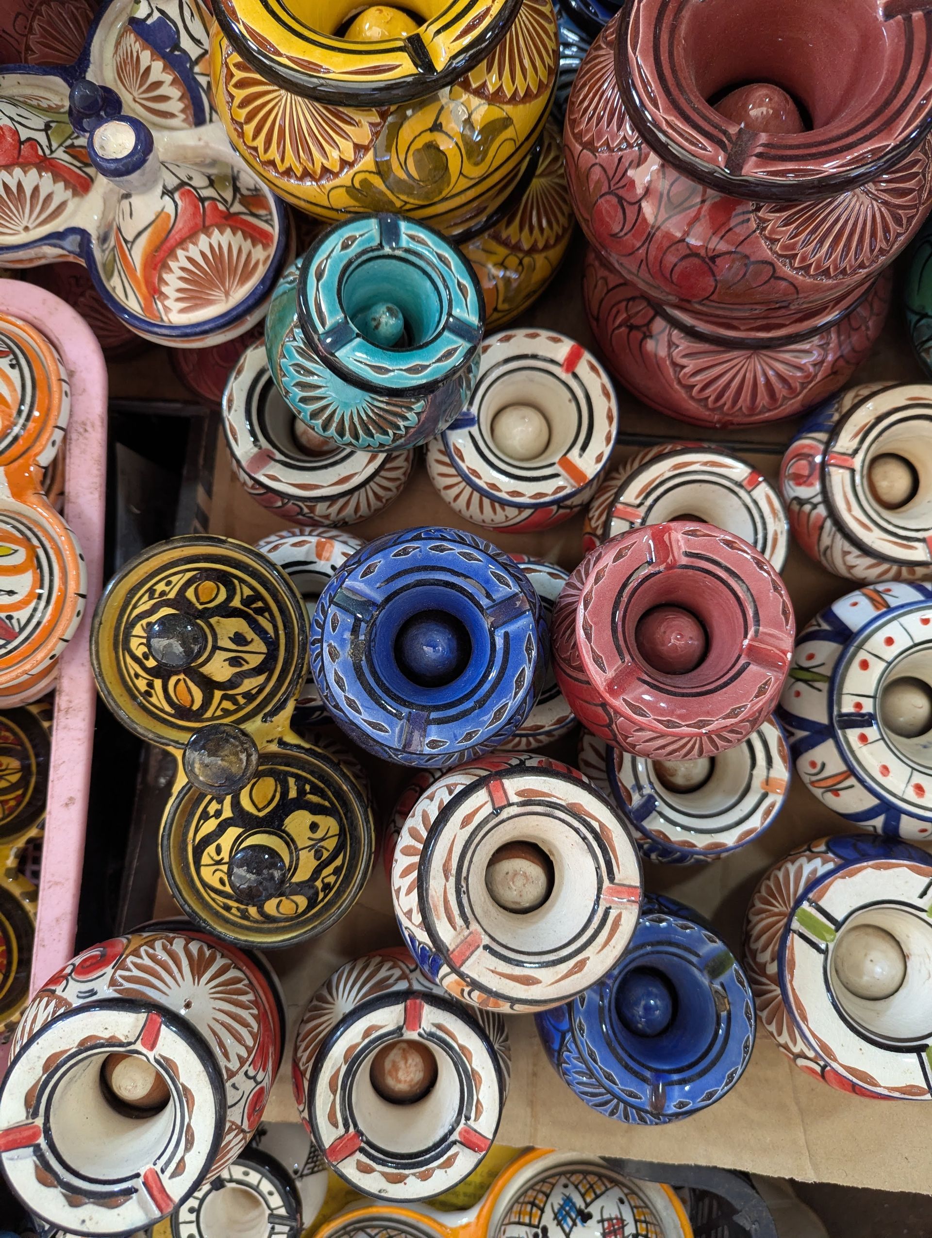 Colorful stacked ceramic pots and bowls with intricate patterns in red, blue, white, and gold