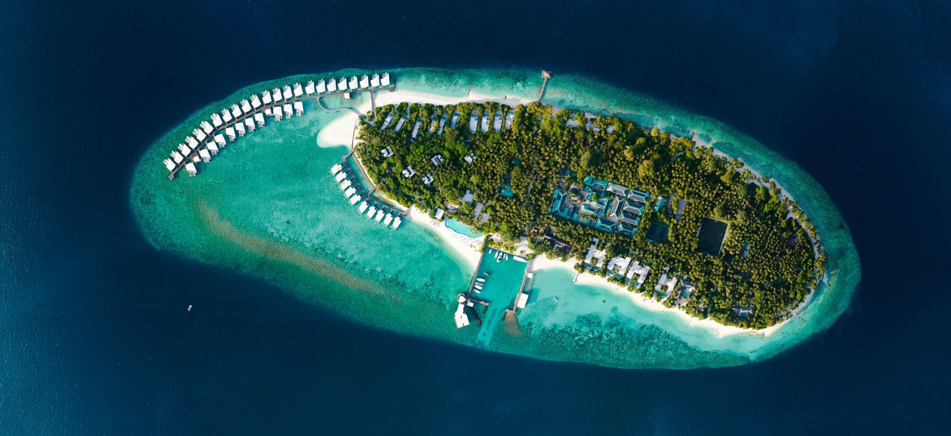 Aerial view of the inclusive lush tropical island resort Amilla surrounded by turquoise water and white sand beaches