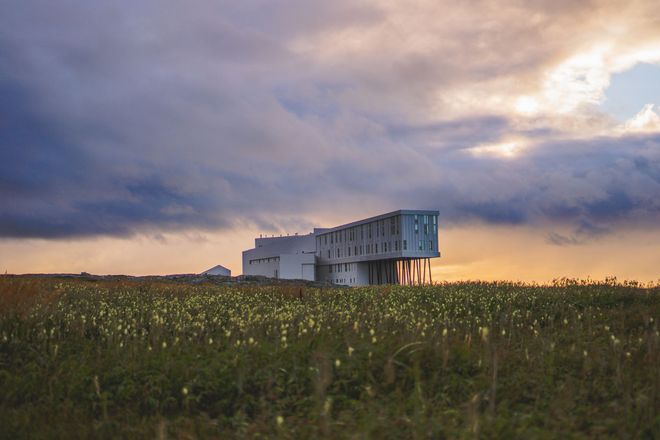 Fogo Island Inn Modern white building, Fogo Island Inn in a grassy field at sunset under a cloudy sky