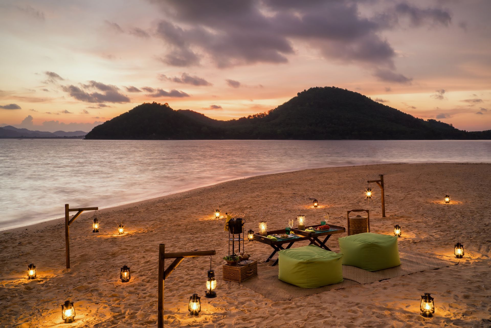 There is a table and chairs on the beach at sunset.