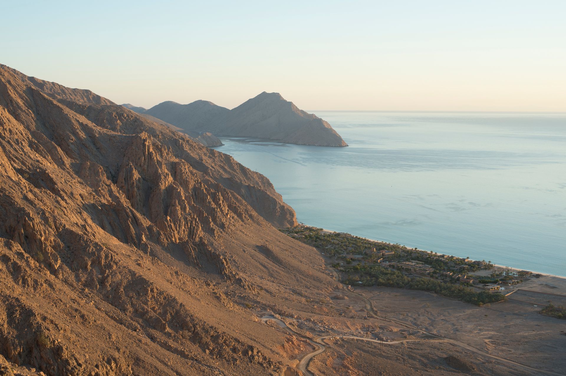 Rocky coastal cliffs overlooking a calm blue sea at sunset