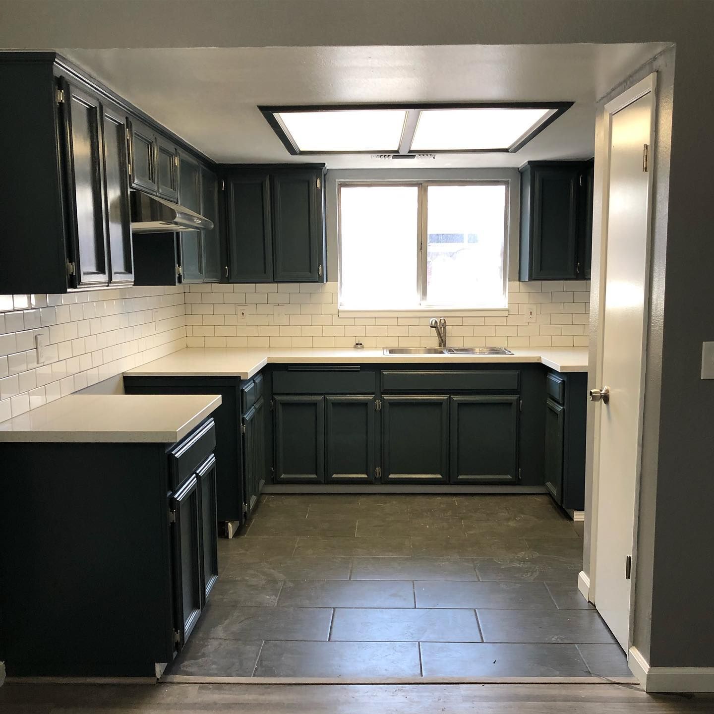 a kitchen with black cabinets and white counter tops