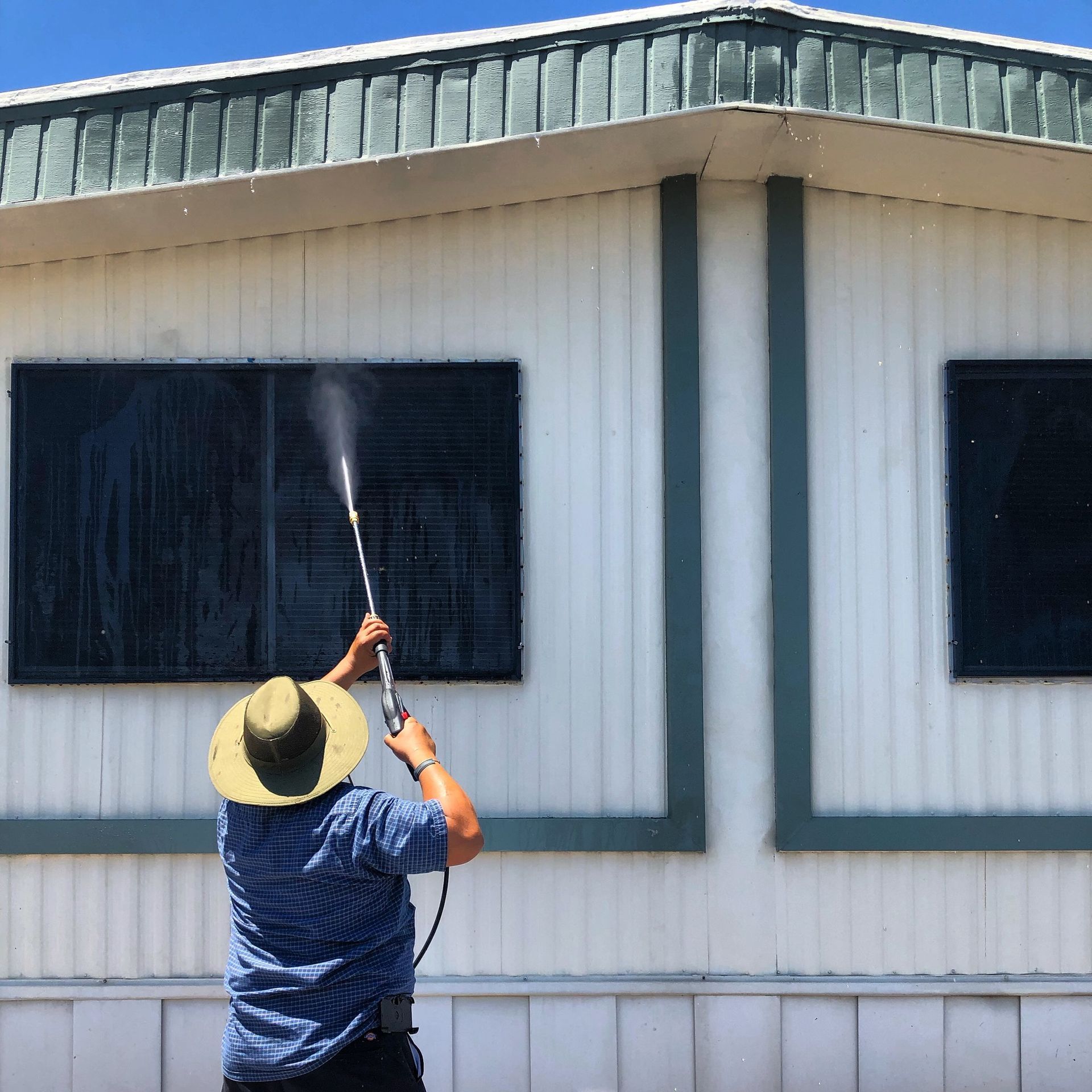 a man in a hat is spraying water on a building