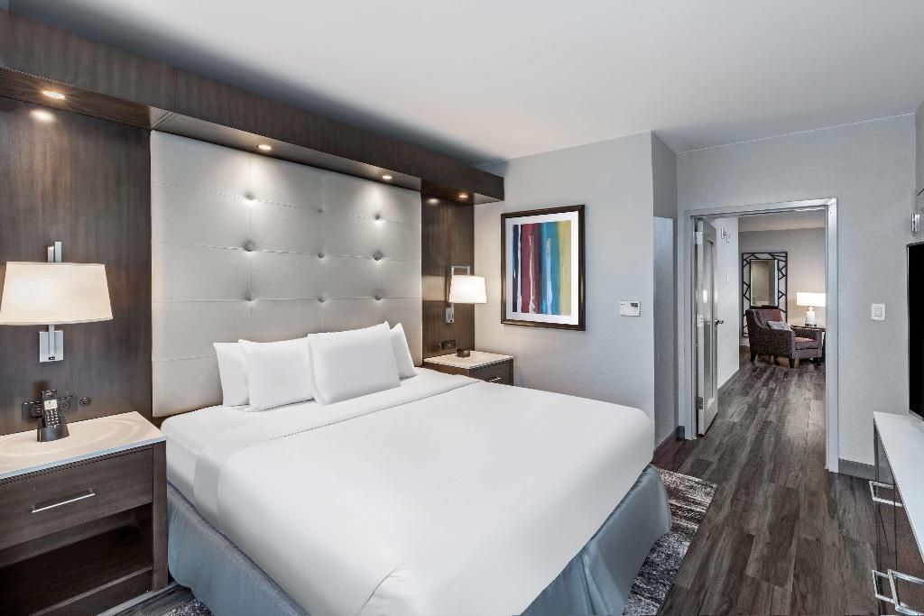 A hotel room with a king size bed and a painting on the wall.