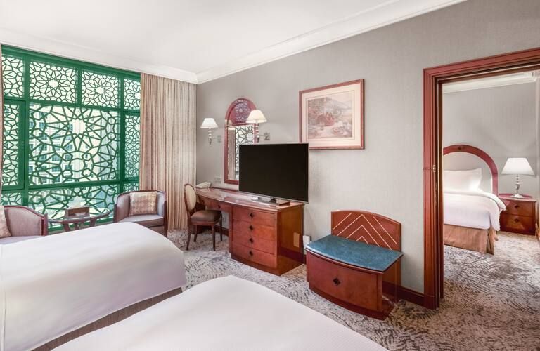 A hotel room with two beds , a desk , a television and a chair.