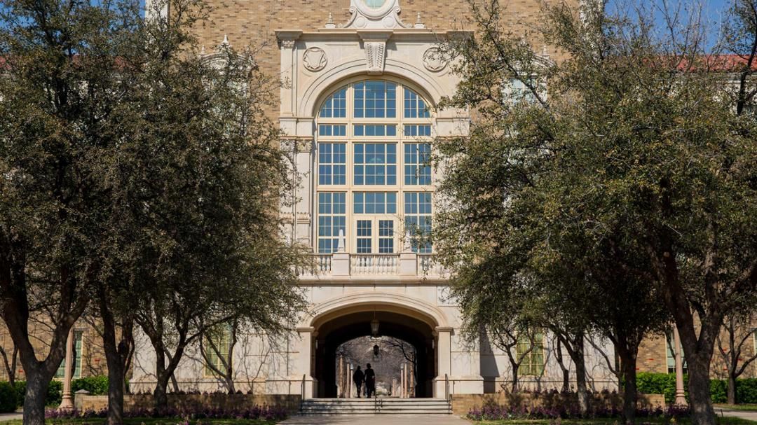 A large building with a clock on the top of it is surrounded by trees.