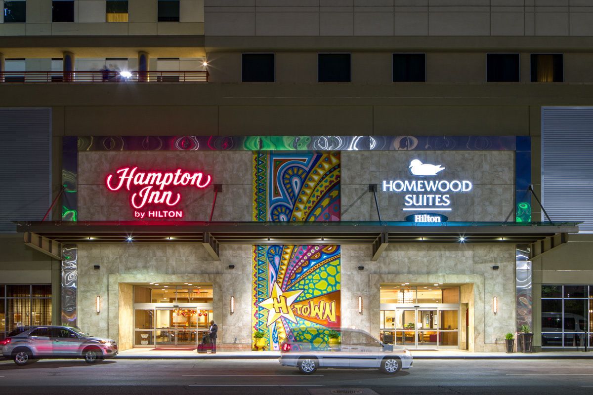 A car is parked in front of the entrance to a hotel.