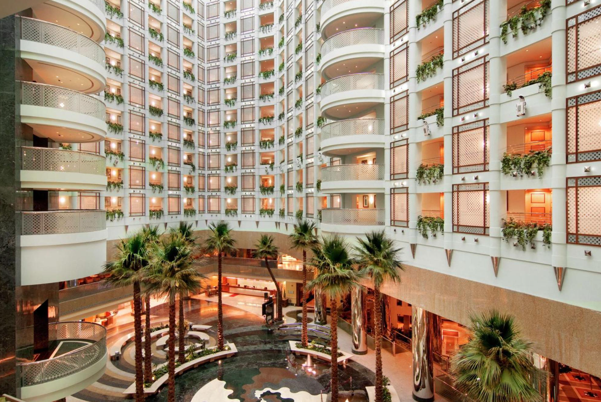 A large building with a lot of windows and palm trees in the middle.