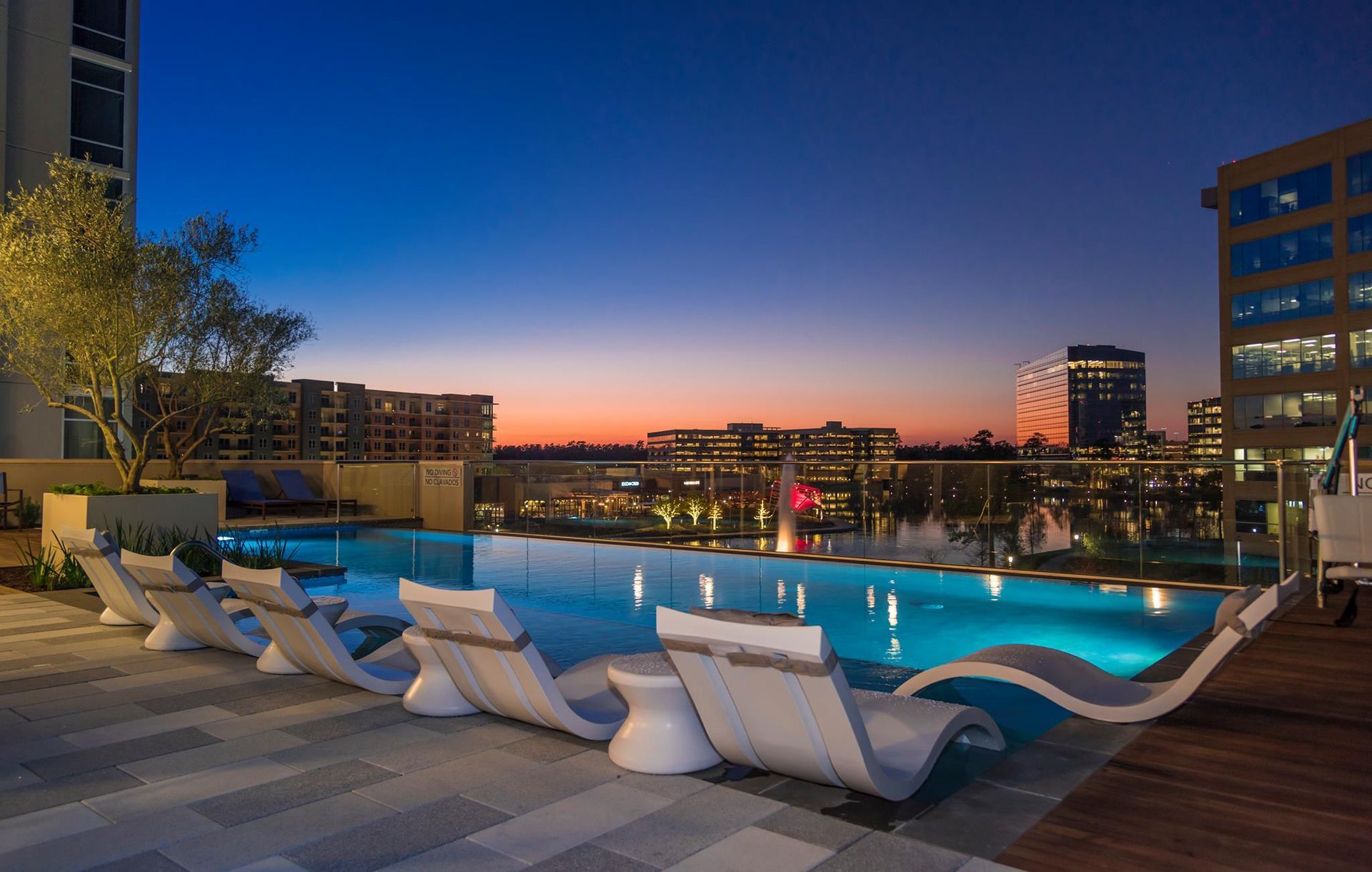 A large swimming pool with chairs around it at night.