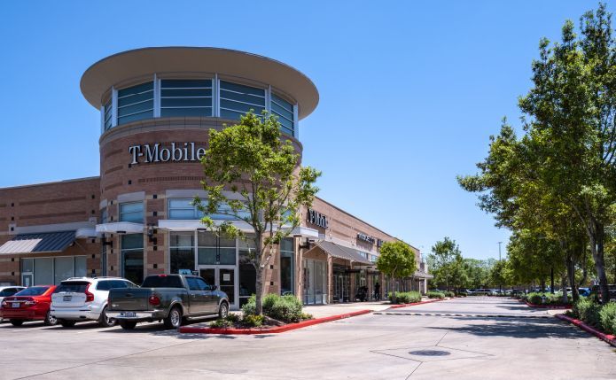 A t-mobile store with cars parked in front of it.
