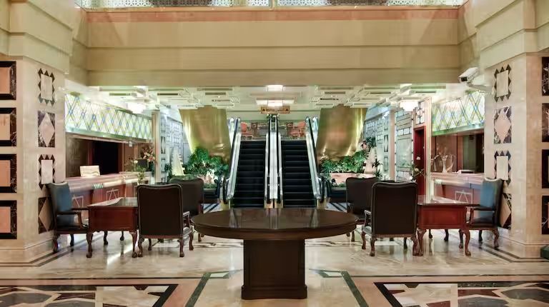 A hotel lobby with a table and chairs and an escalator.