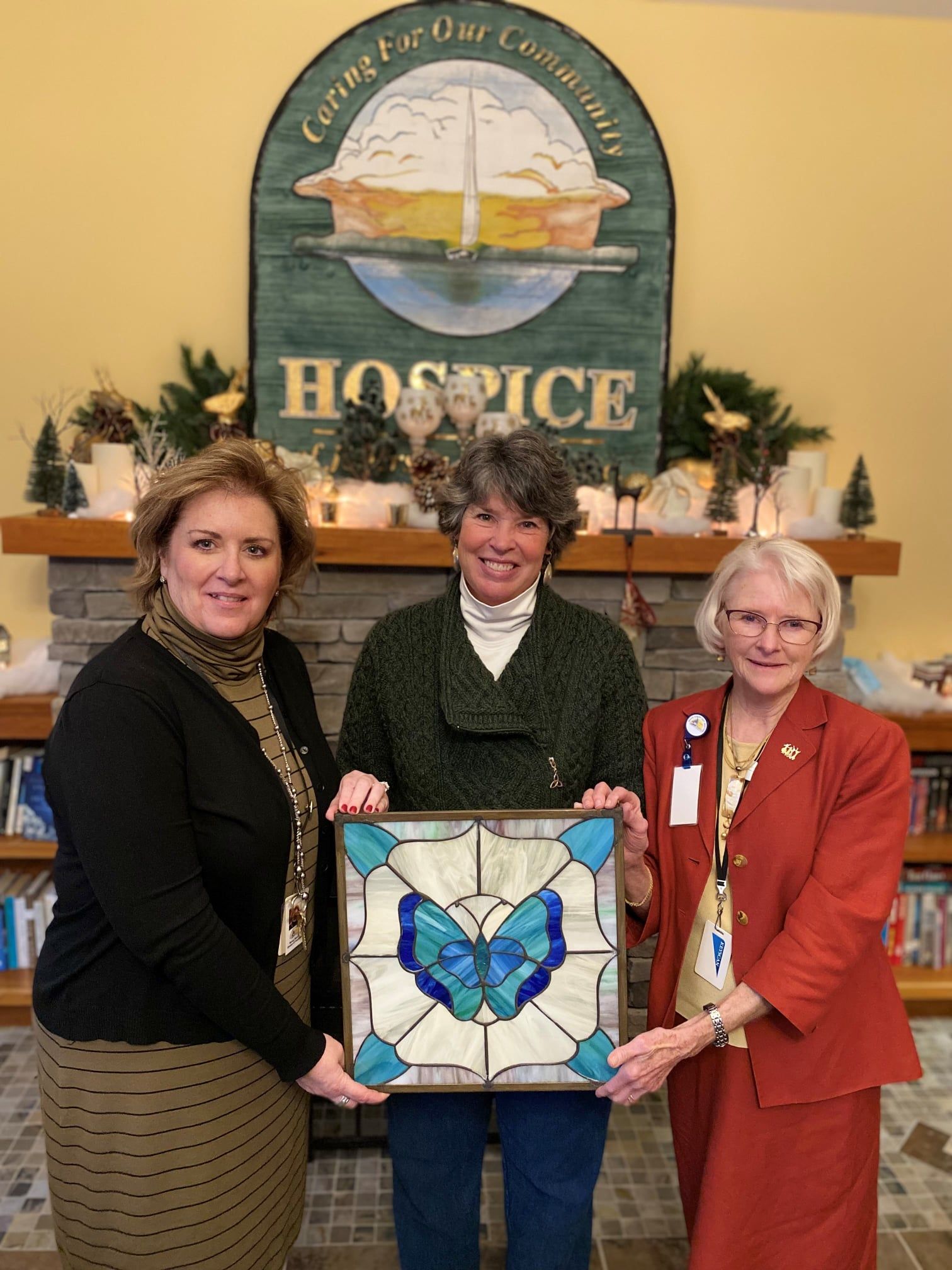 Three women stand in front of a sign that says hospice