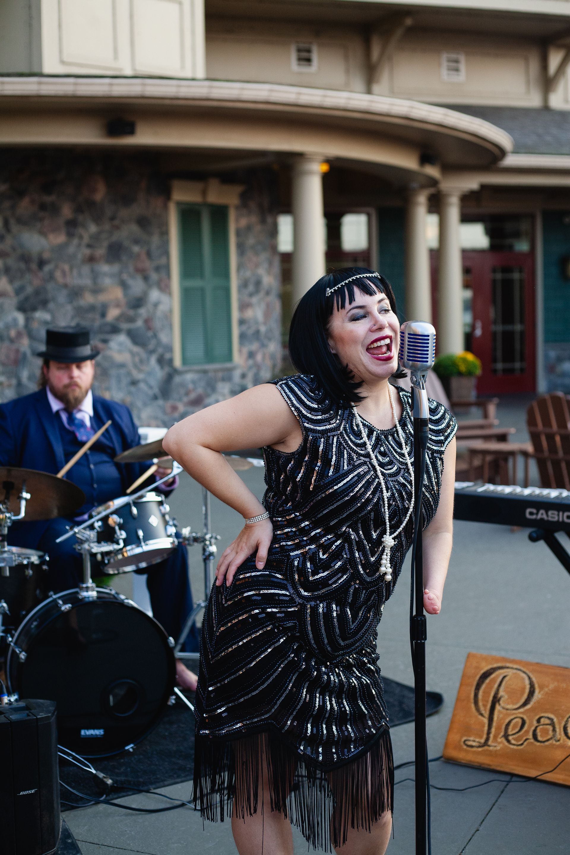 A woman in a flapper dress is singing into a microphone.