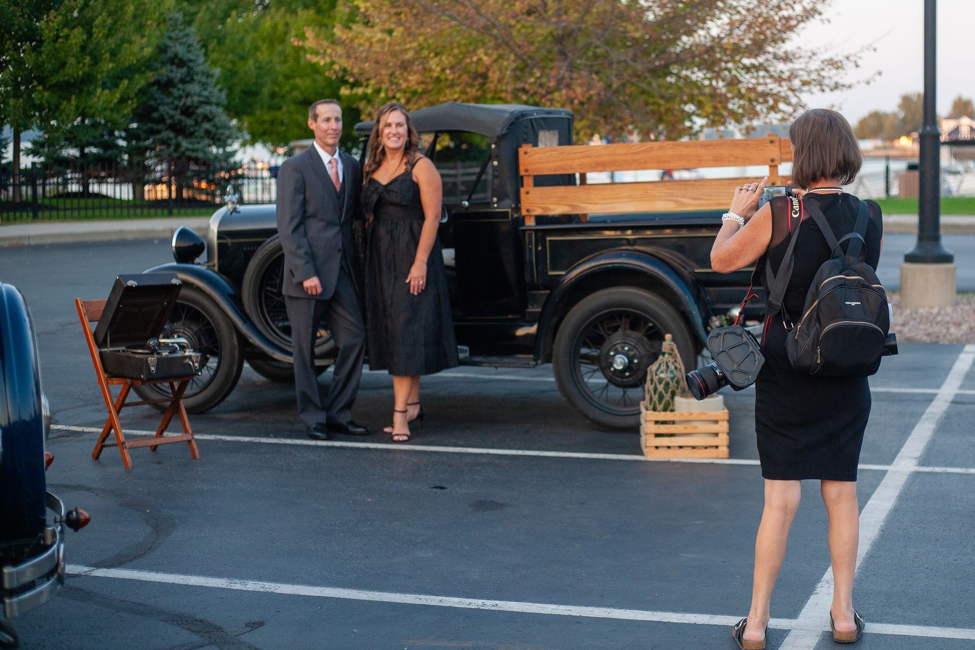 A woman is taking a picture of a man and woman in front of an old truck.