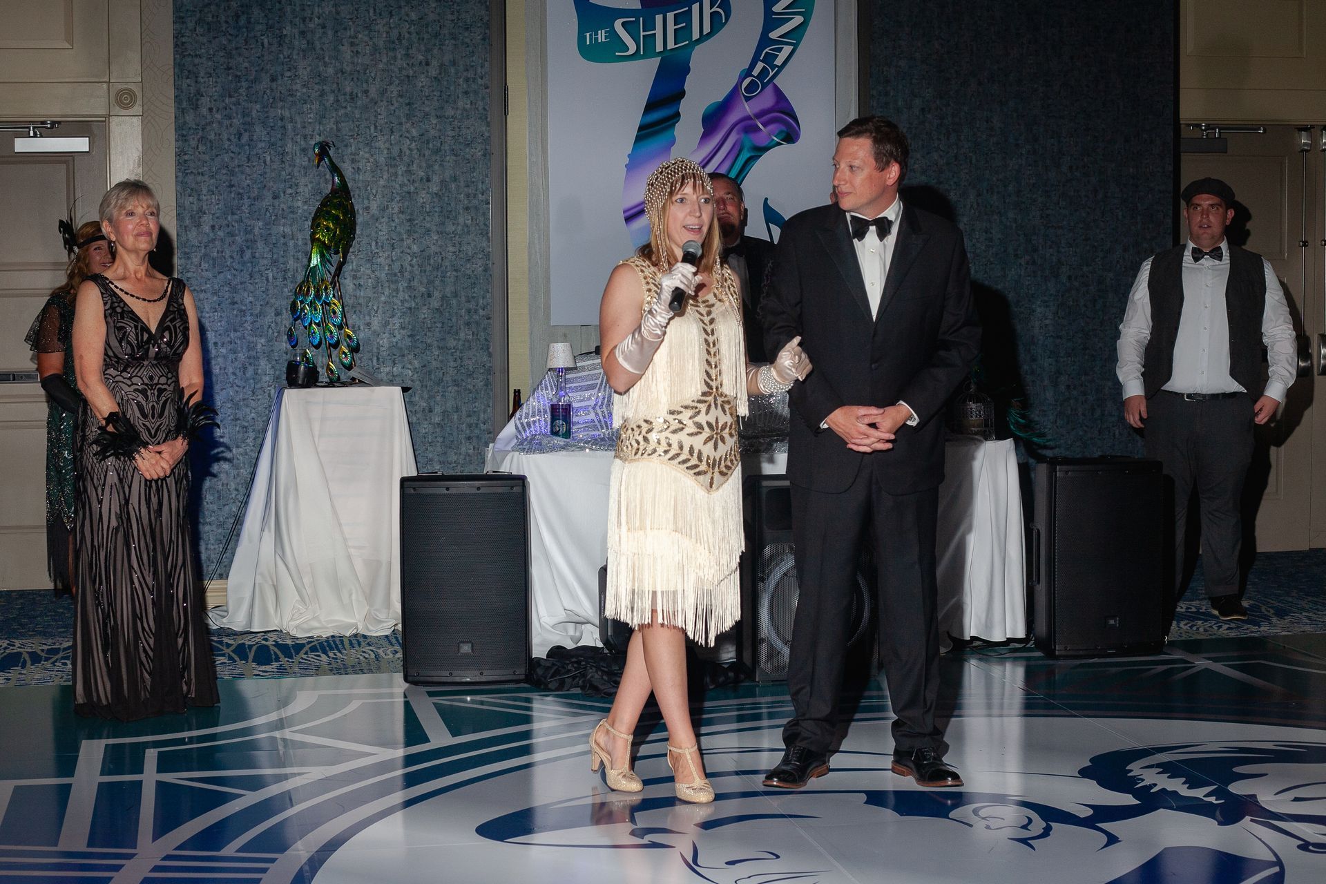 A woman in a flapper dress is standing next to a man in a tuxedo