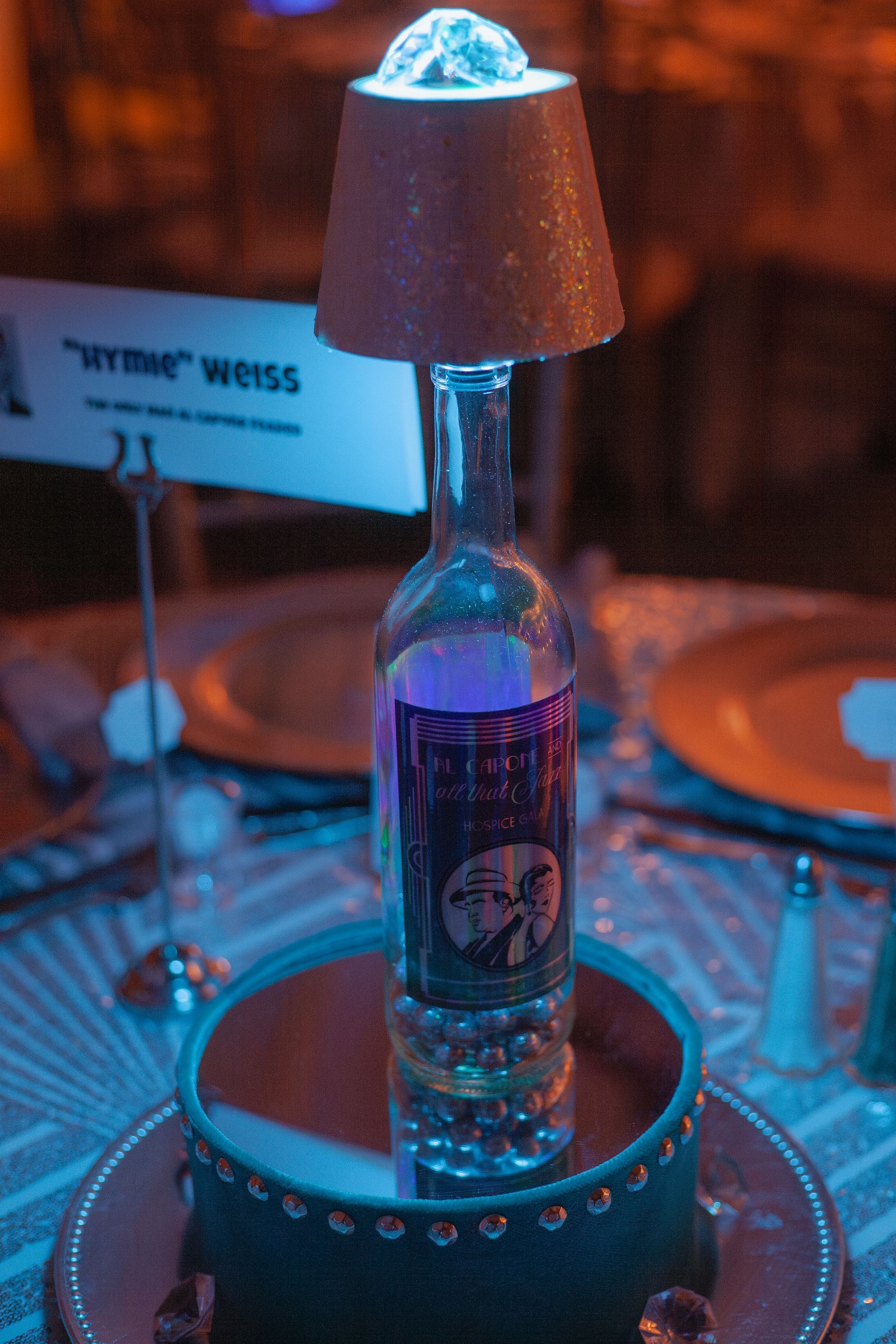 A bottle of vodka with a lamp on top of it on a table.