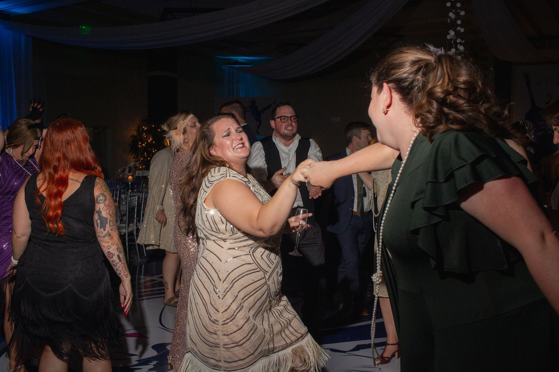 A group of women are dancing on a dance floor at a wedding reception.
