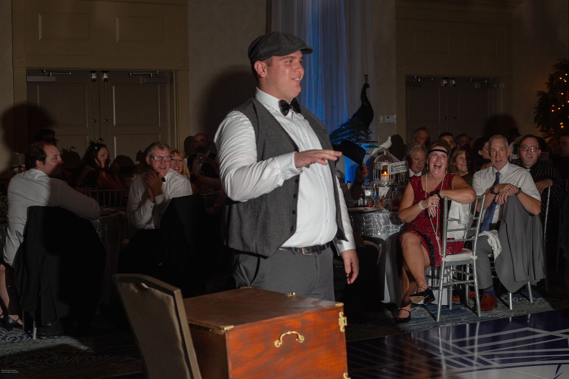 A man in a hat is standing in front of a crowd of people at a party.