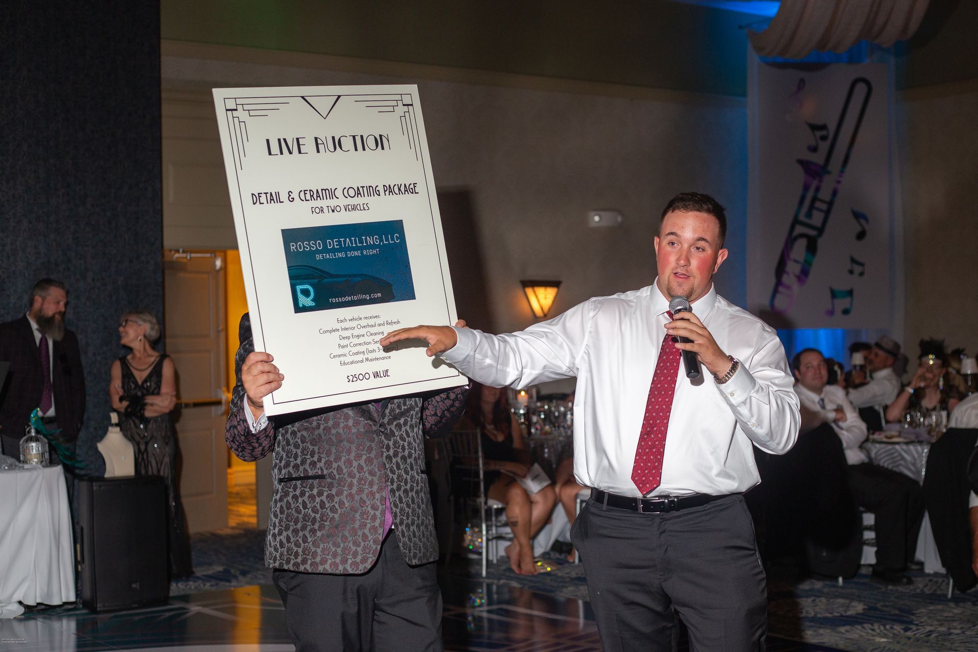 A man is holding a sign in front of his face while holding a microphone.