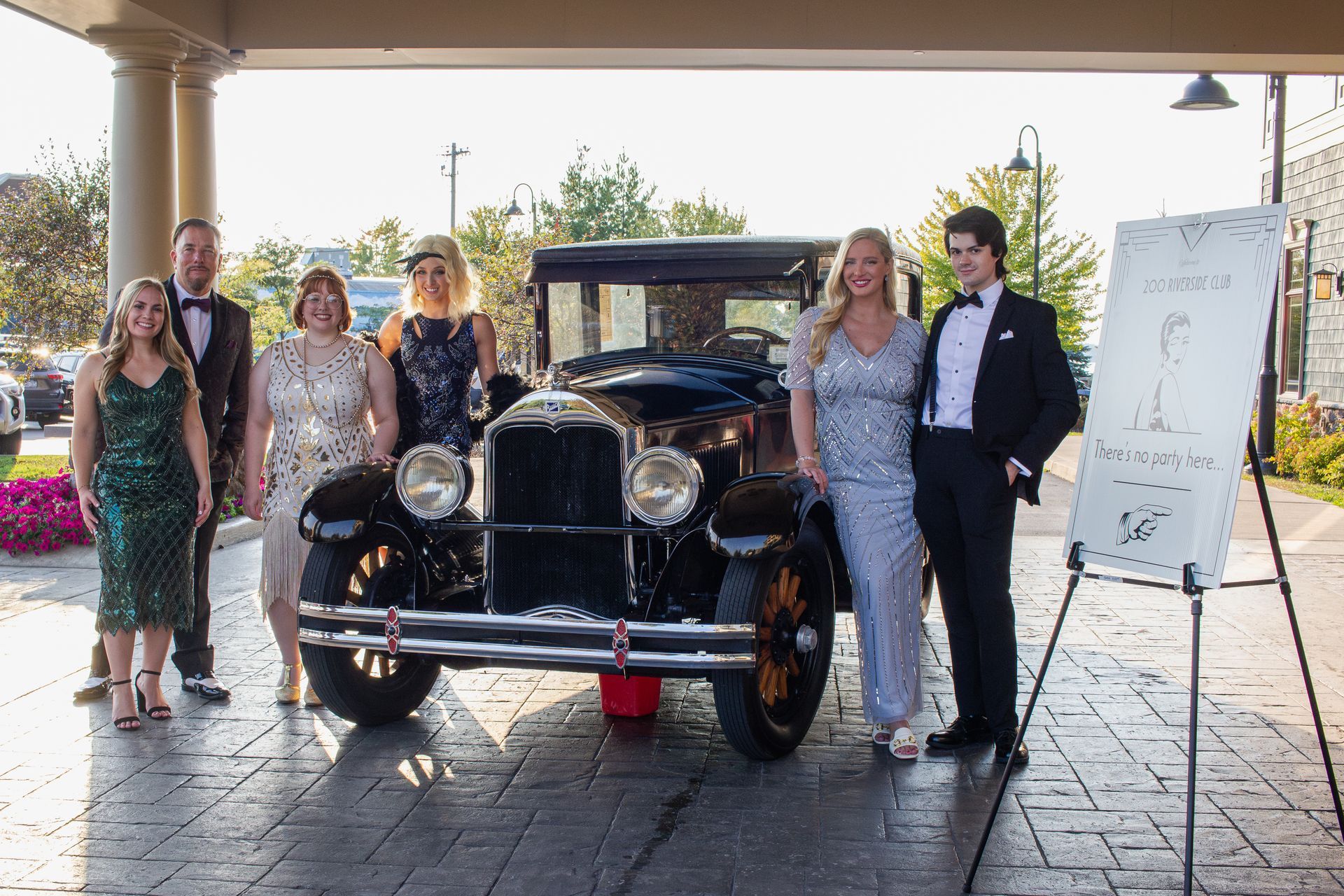 A group of people are standing in front of an old car.