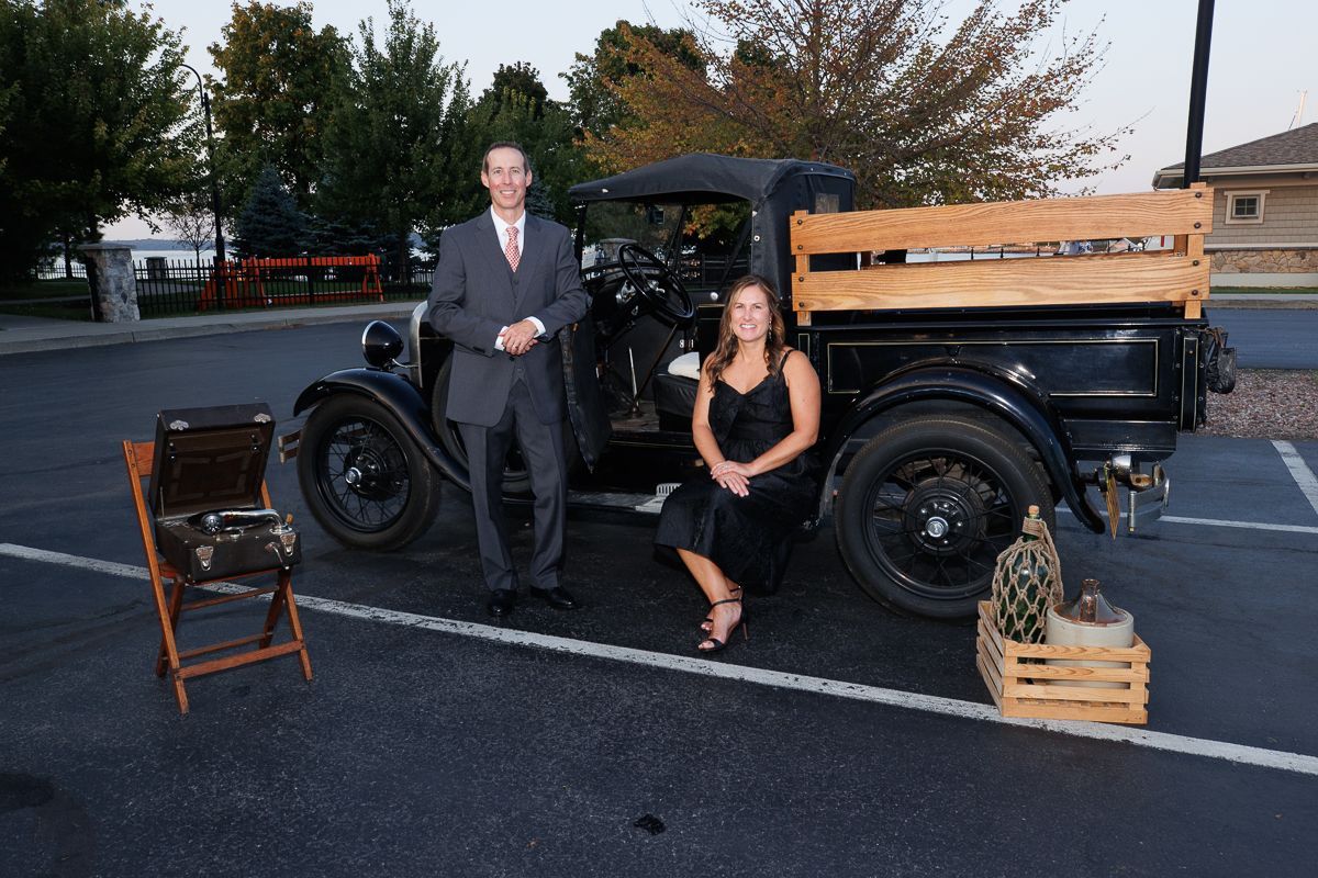 A man and a woman are standing next to an old truck in a parking lot.