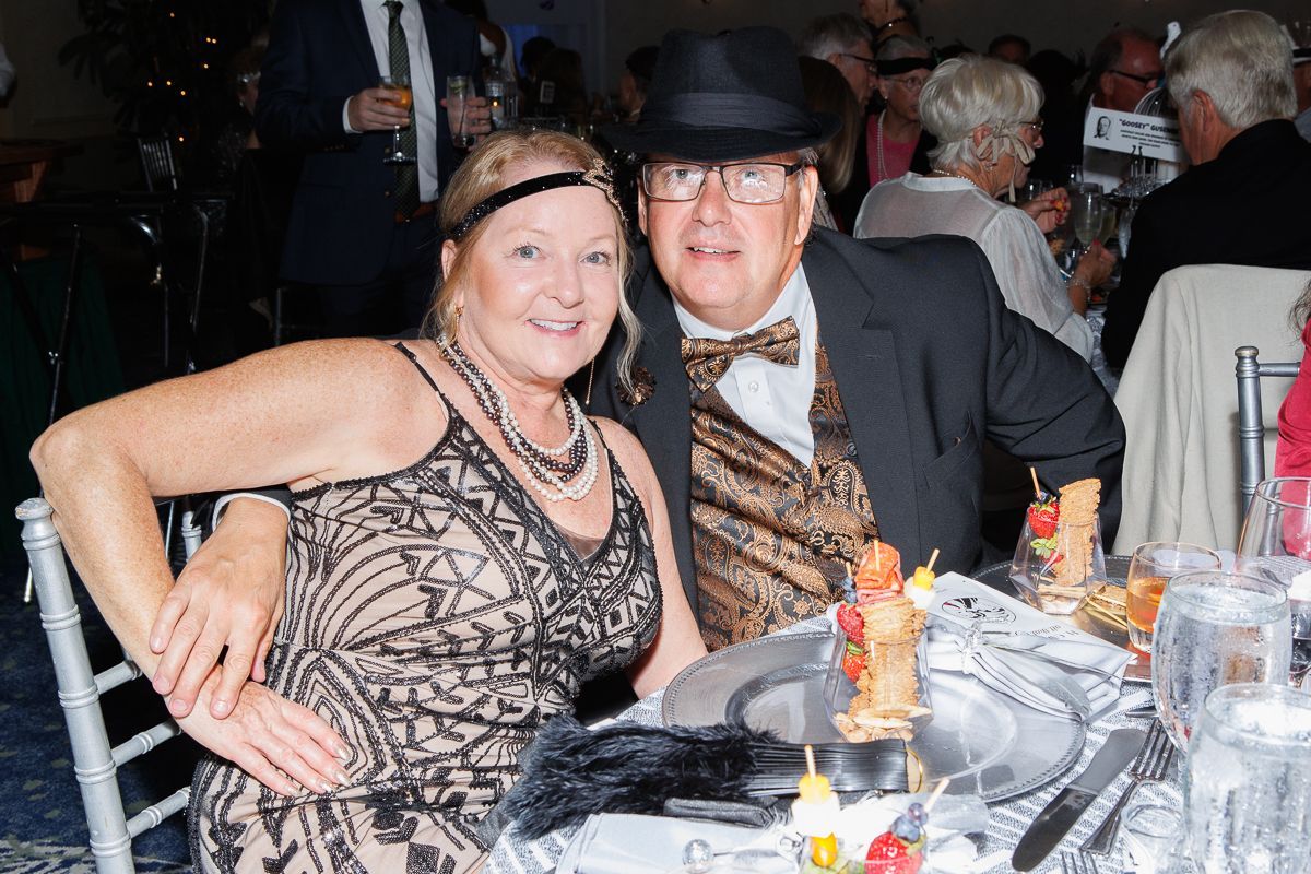 A man and a woman are sitting at a table at a party.