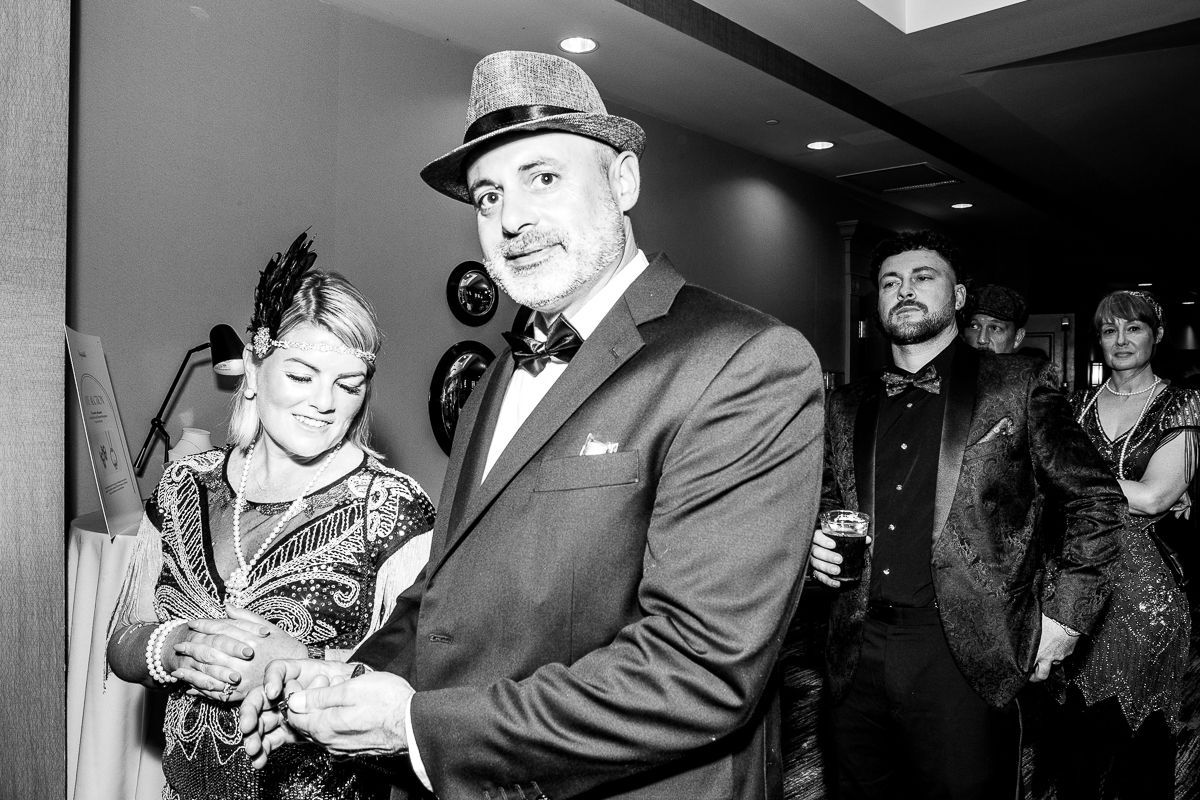 A man in a suit and hat is standing next to a woman in a dress.