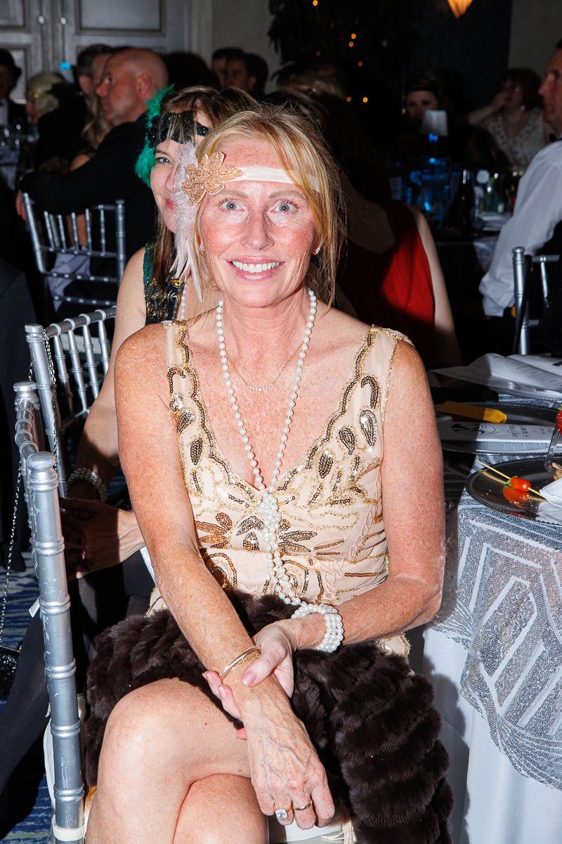 A woman in a flapper dress is sitting in a chair at a party.