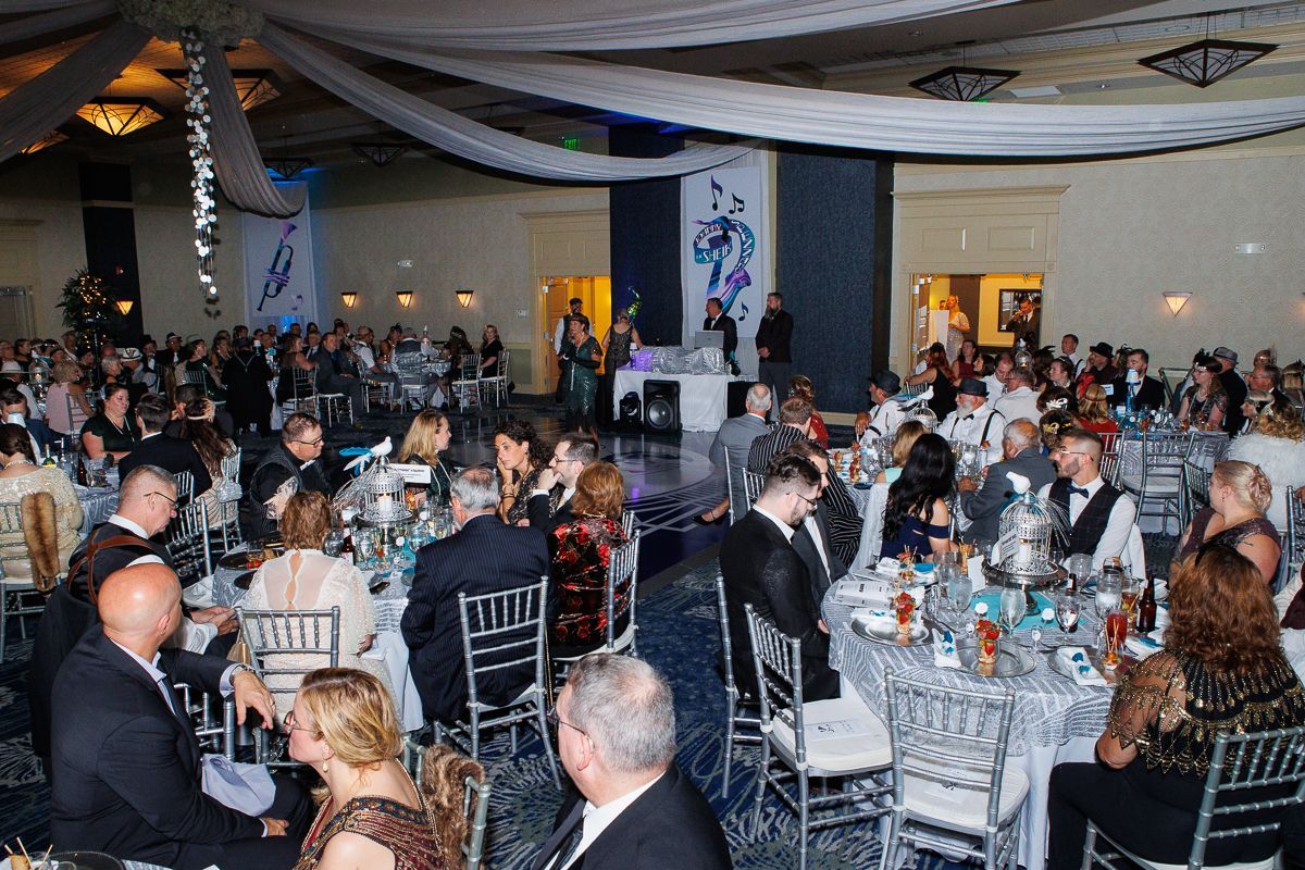 A large group of people are sitting at tables in a large room.