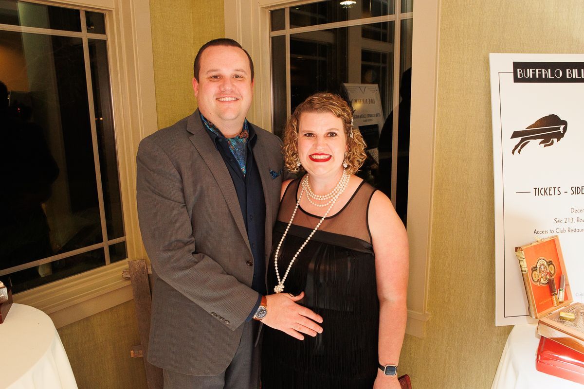 A man and a woman are posing for a picture in front of a window.