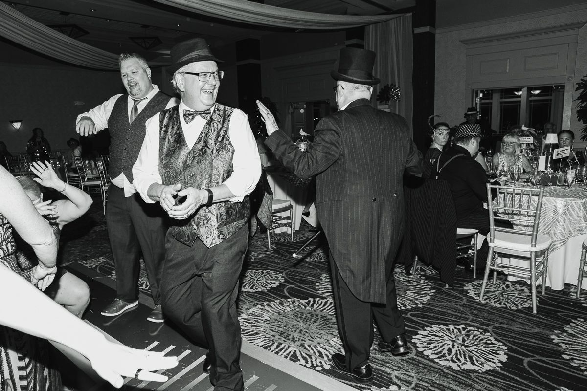 A black and white photo of a group of people dancing at a party.