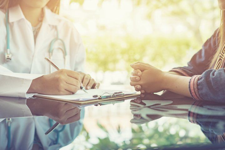 A doctor is talking to a patient at a table.