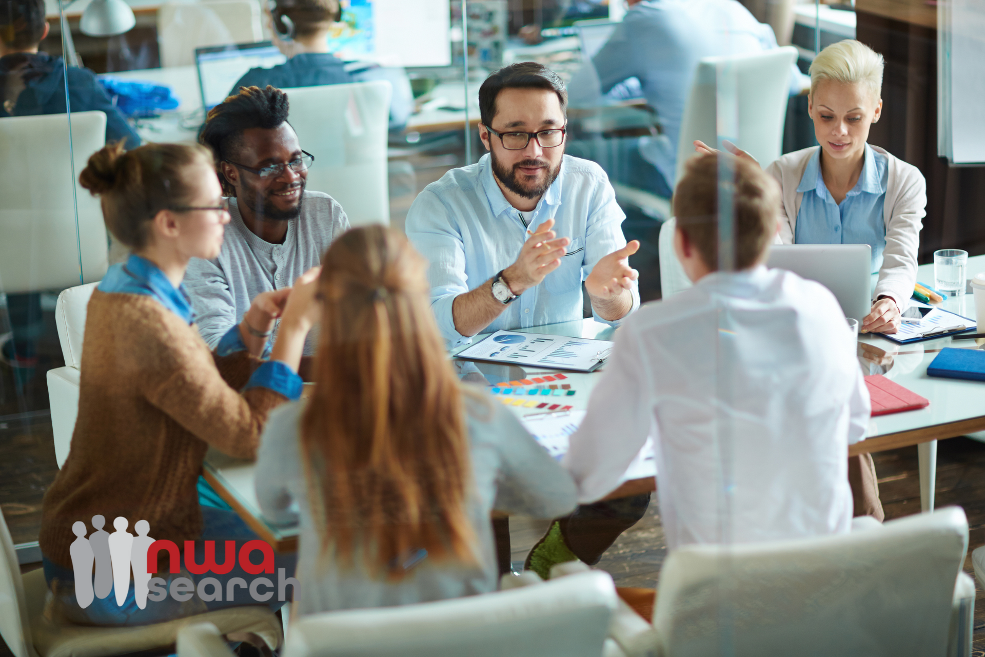 A group of people are sitting around a table having a meeting.