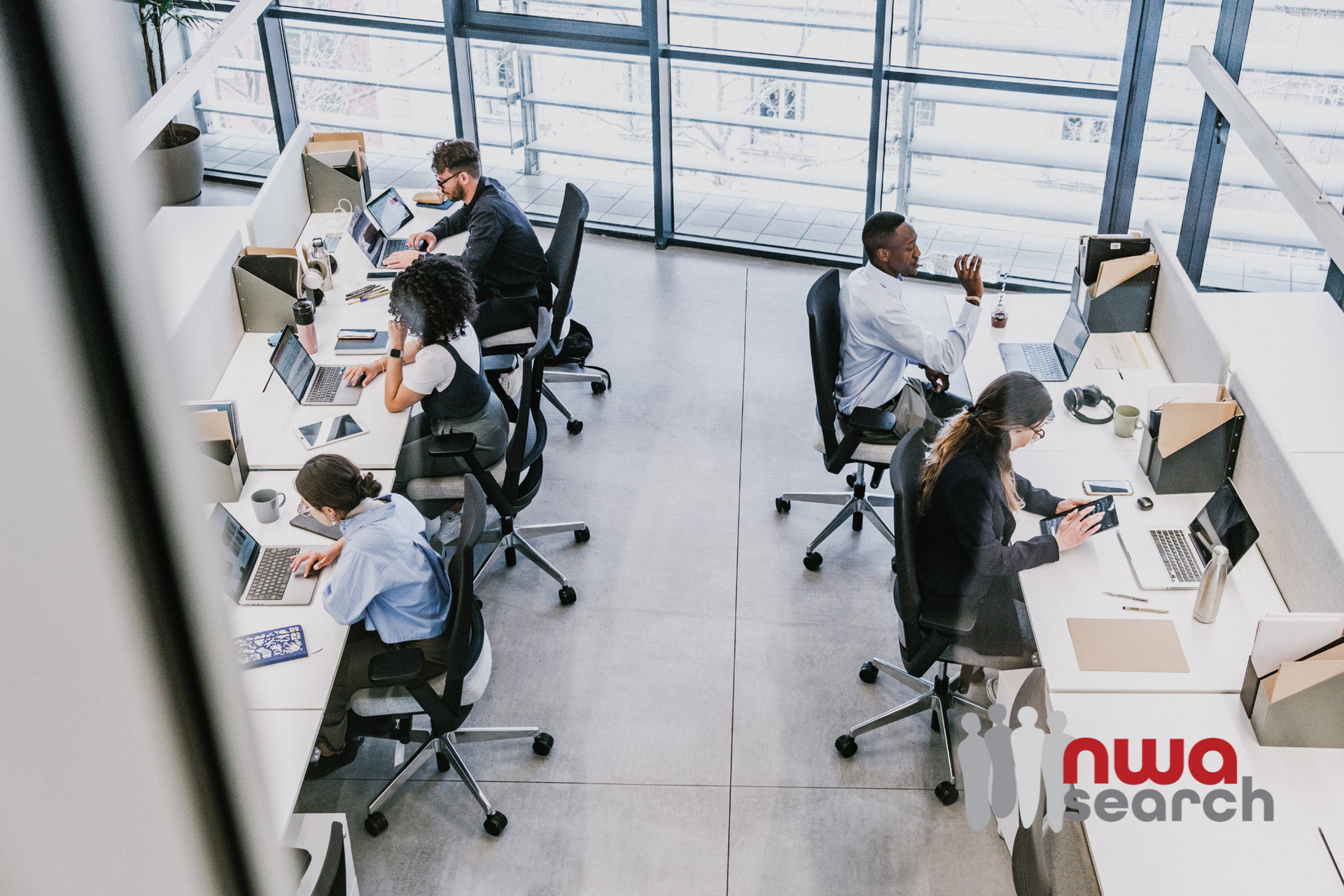 A group of people are sitting at desks in an office.